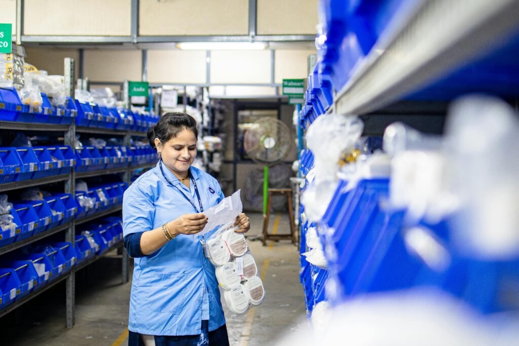 A woman in blue uniform organizing inventory in a warehouse aisle, focused on efficiency.