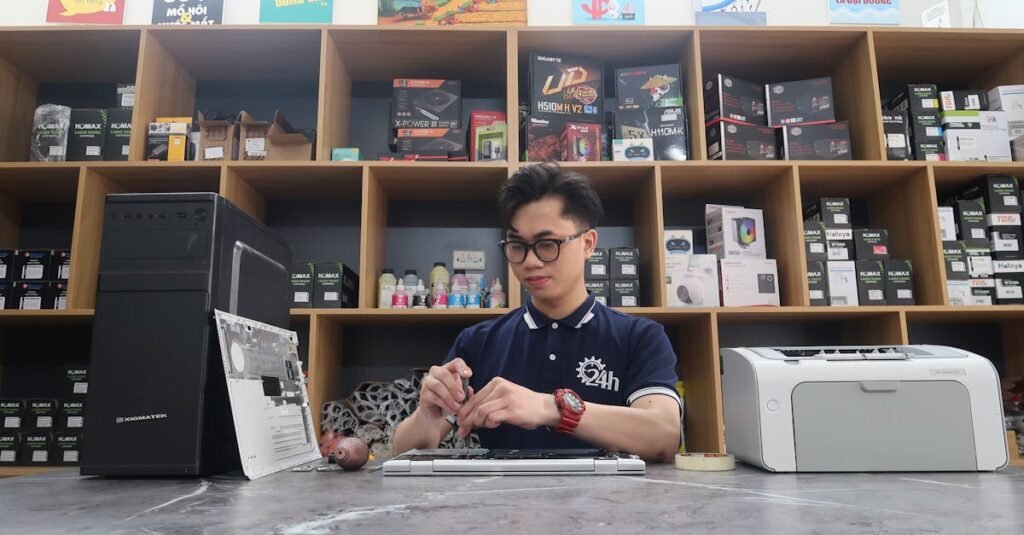 Young technician fixing a computer in a modern electronics store setting.