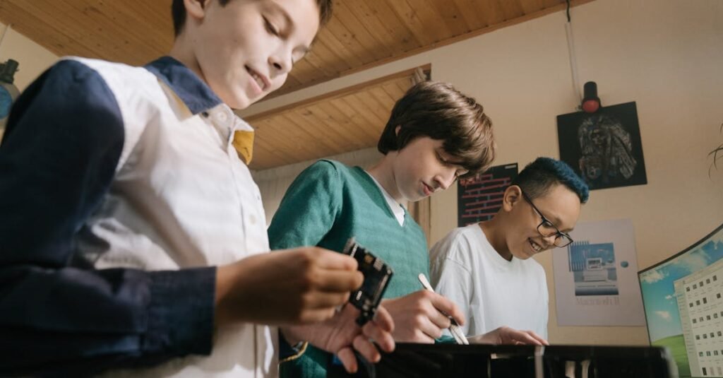 Three teenagers collaborate on a computer project indoors, focusing on microchips and technology.