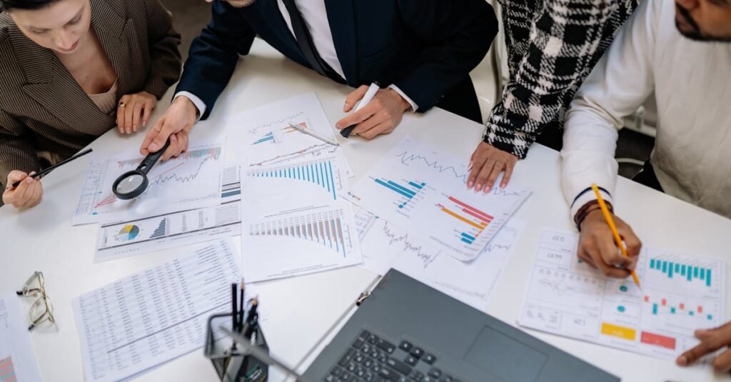 A group of professionals reviewing financial charts in an office meeting setting.
