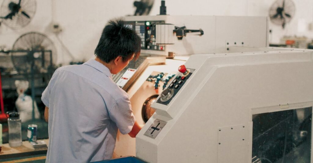Worker focusing on operating industrial machinery in a factory setting.
