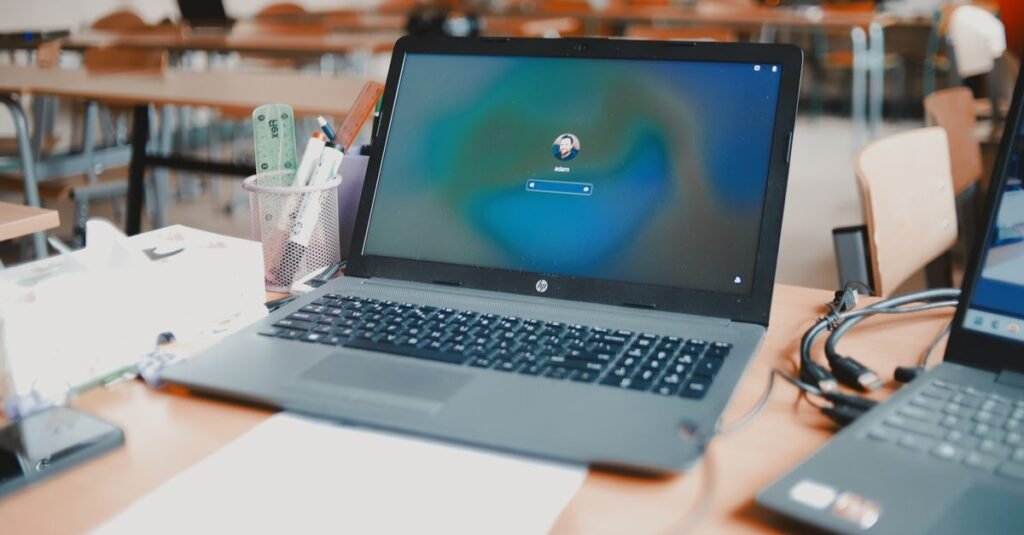 A close-up of a laptop on a desk in a classroom setting, ready for educational use.