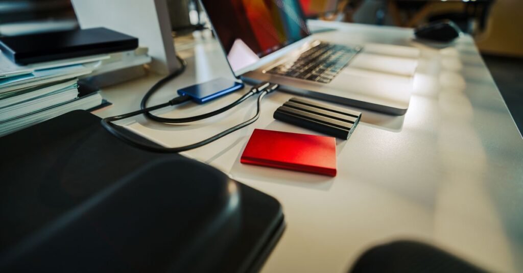 A neatly organized office desk featuring a laptop and several external hard drives, perfect for a digital workspace.