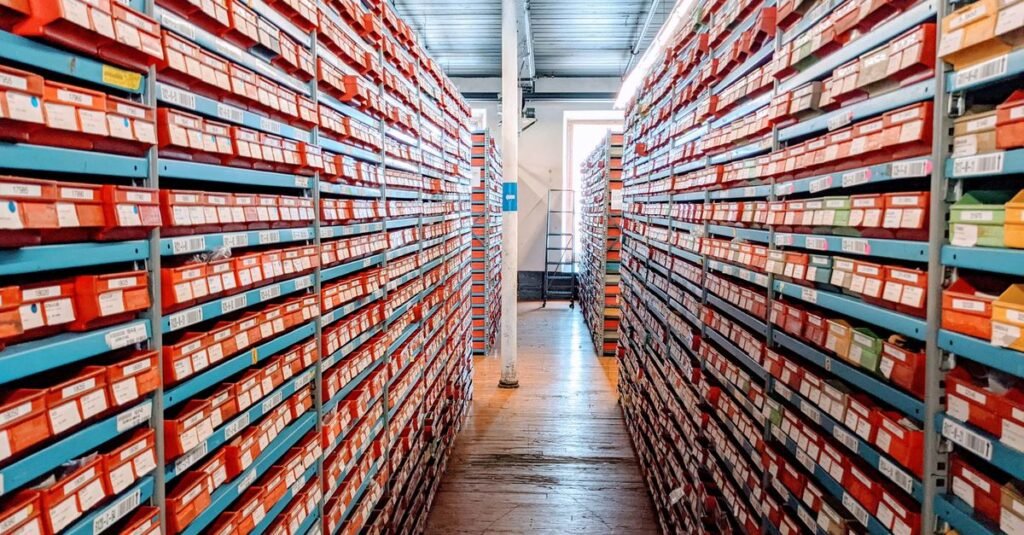 A well-organized warehouse aisle filled with red shoe boxes on shelves, showcasing efficient inventory storage.