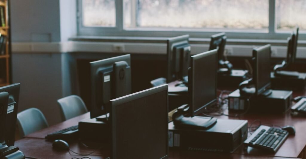 Spacious computer lab with rows of monitors and keyboards in a sunlit room.