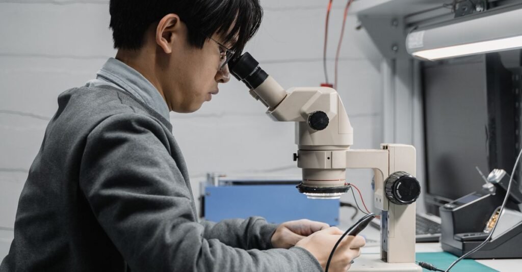 A focused technician repairing electronic components with a microscope in a lab.