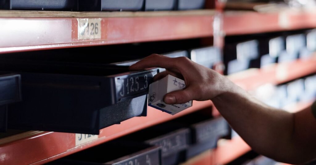Hand reaching for storage bin in organized warehouse shelving. Perfect for logistics and inventory themes.