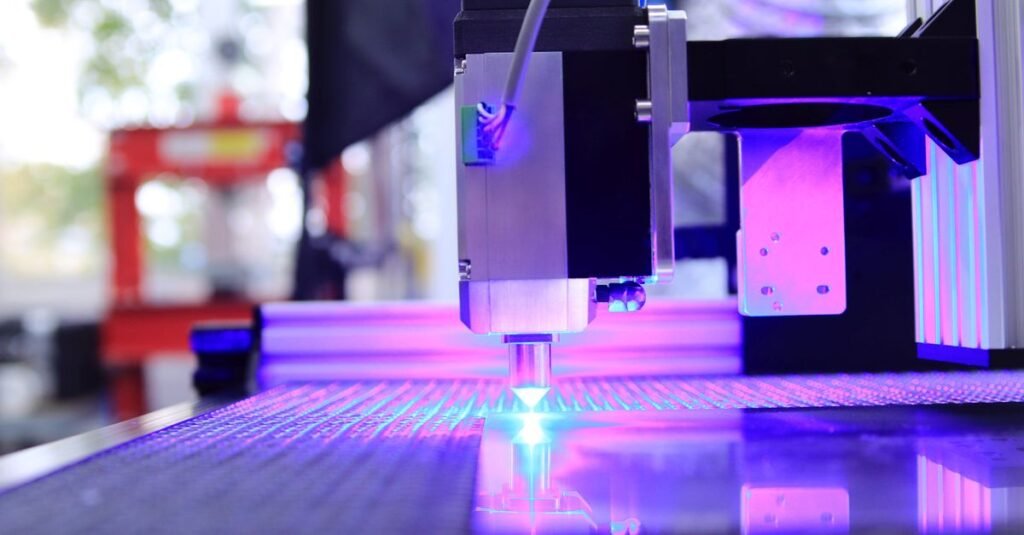 Close-up of a laser engraving machine working indoors with blue light reflection.