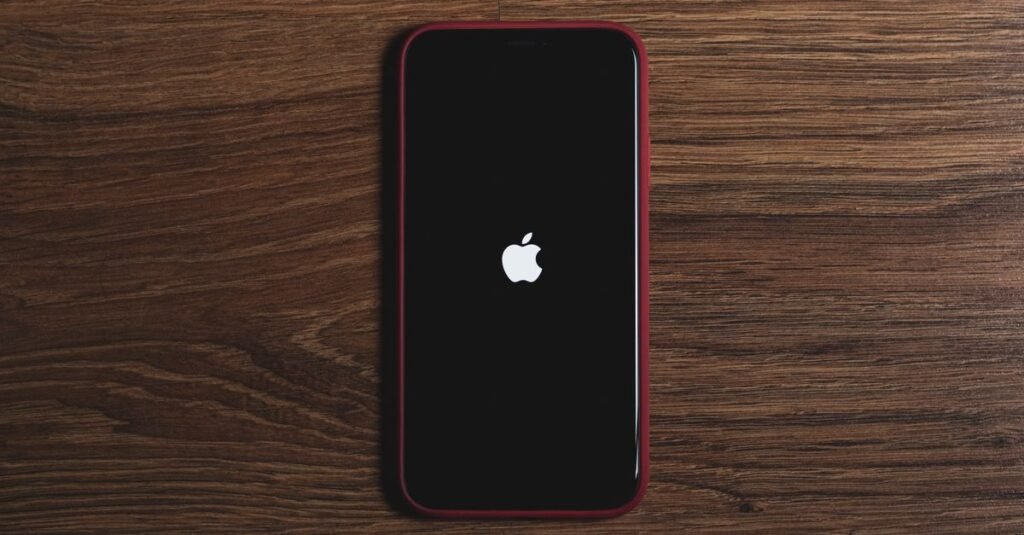 Minimalist flat lay of a smartphone with Apple logo on a wooden surface, ideal for tech and gadget themes.
