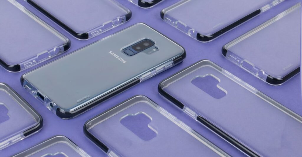 Close-up of a Samsung phone surrounded by transparent cases on a purple surface, showcasing modern technology.