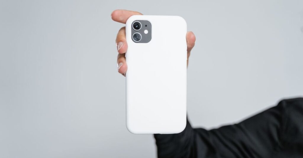 Close-up of a hand holding a smartphone with a white case against a plain background.